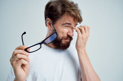 Portrait of young man making face against gray background