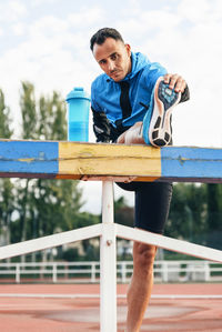 Portrait of young man standing against railing