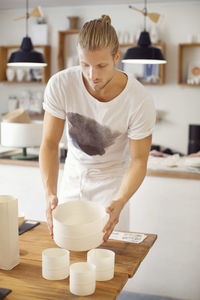 Young man holding craft products in crockery workshop