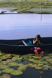 Woman photographing water lilies from boat