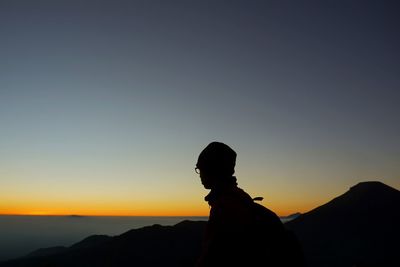 Silhouette man standing on mountain against sky during sunset