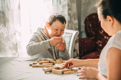 Elderly woman down syndrome builds tower of wooden cubes, development of cognitive fine motor skills