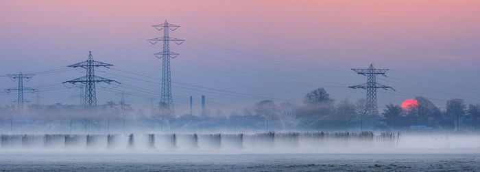 Scenic view of electricity pylon against sky during foggy weather