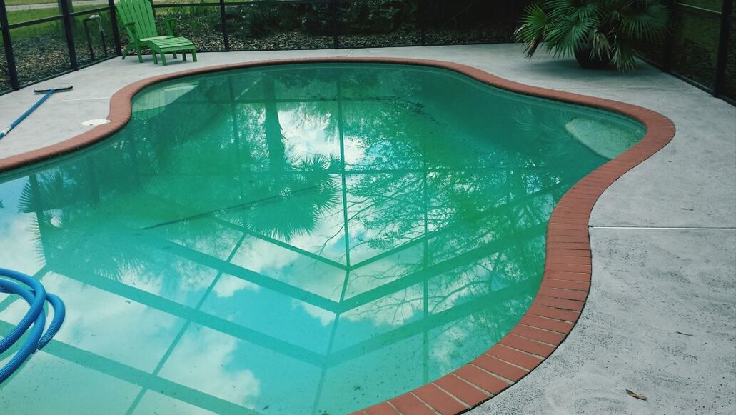 empty, railing, tree, high angle view, built structure, day, swimming pool, absence, reflection, green color, sunlight, no people, outdoors, architecture, park - man made space, blue, pattern, transportation, nature, seat