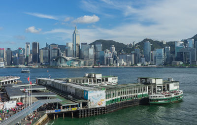 Modern buildings by river against sky in city