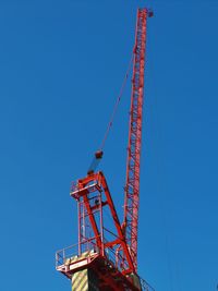 Low angle view of crane against clear blue sky