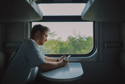 A man using a smartphone while traveling by railway train