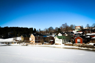 Houses and buildings against clear blue sky in winter