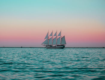 Sailboat sailing on sea against sky during sunset