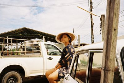 Portrait of woman wearing hat while standing by car