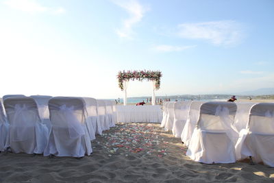 Chairs arranged at beach for wedding ceremony