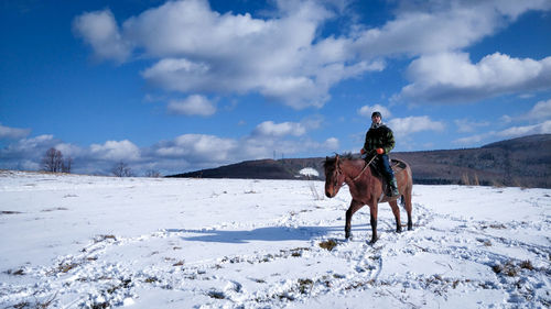 Man riding horse on snow covered land