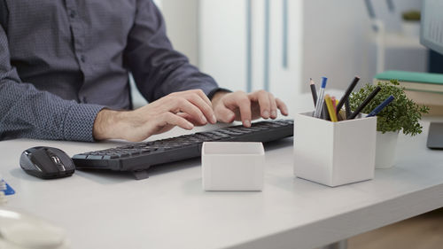 Midsection of businessman using laptop on table