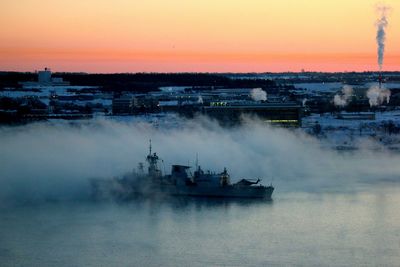 Navy frigate leaving harbor at dawn