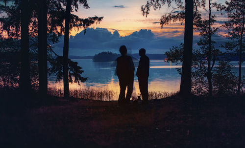 Silhouette couple standing on beach at sunset