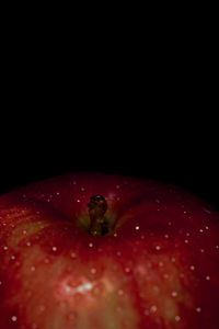 Close-up of wet red apple against black background