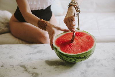 Midsection of woman eating watermelon on table