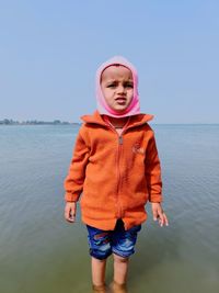 Full length of boy standing in sea against clear sky
