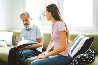 Side view of woman using laptop while sitting on sofa at home