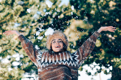 Portrait of woman on snow covered tree during winter