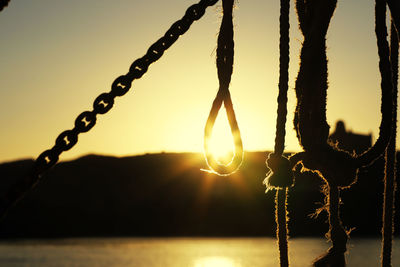 Close-up of silhouette rope against sky during sunset