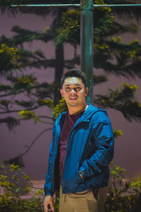 Portrait of young man standing against trees