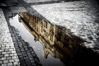 Reflection of building in puddle on street