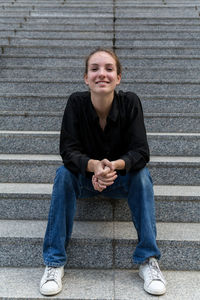 Portrait of young woman smiling while sitting on staircase