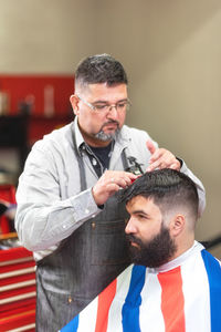 Barber cutting male customer hair in salon