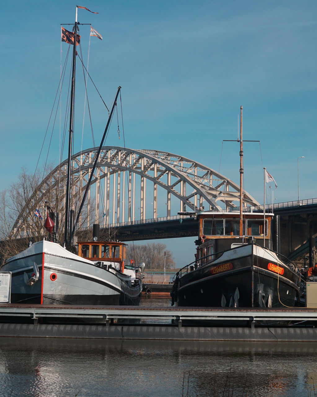 transportation, bridge - man made structure, connection, mode of transport, architecture, built structure, sky, land vehicle, day, river, outdoors, car, water, cloud - sky, road, low angle view, no people, nautical vessel, city