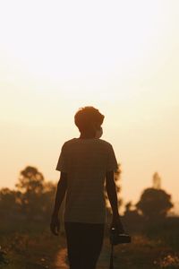 Rear view of silhouette man standing on land against sky during sunset