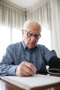 Senior man controlling his blood pressure and writing down the result