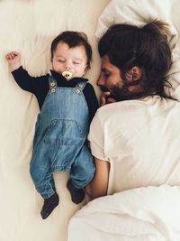 High angle view of father and daughter sleeping on bed