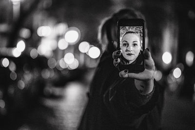 Portrait of young woman using phone at night during winter