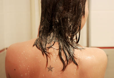 Rear view of shirtless woman in bathroom