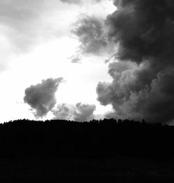 Silhouette landscape against cloudy sky