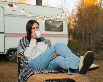 Portrait of young woman sitting on car