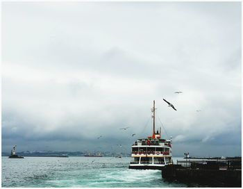 Boats sailing in sea against cloudy sky