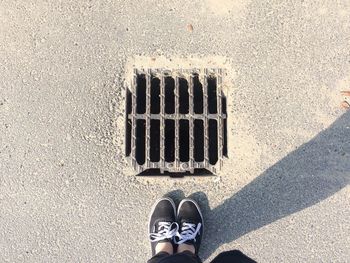 Low section of man standing by manhole