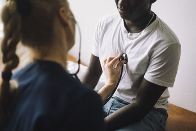 Female doctor listening to patient's heartbeat using stethoscope in clinic