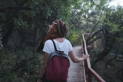 Full length of woman standing by trees in forest