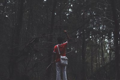 Rear view of man gesturing while standing in forest