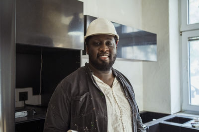 Portrait of smiling male construction manager wearing hardhat in apartment