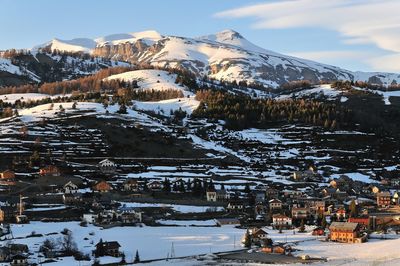 Snow covered houses by mountain against sky