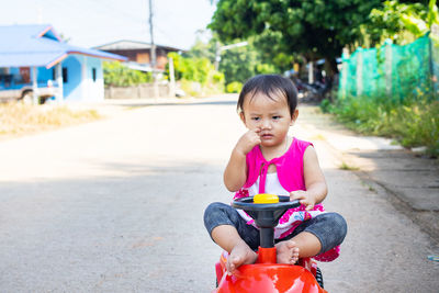 Cute girl riding horse toy car on road