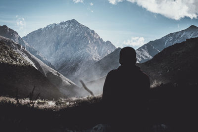 Rear view of man looking at mountains against sky