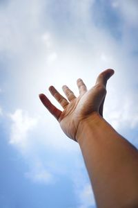 Low angle view of human hand against sky