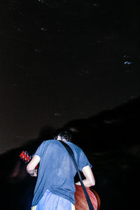 Rear view of man with umbrella standing at night