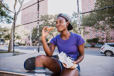 Young woman looking away while sitting in city