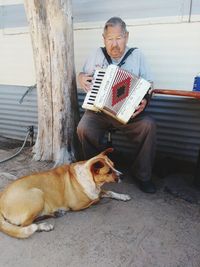 Old man playing accordion with dog at his feet